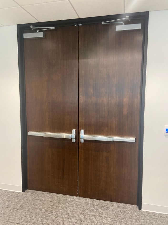 A man is installing a door lock on a wooden door.