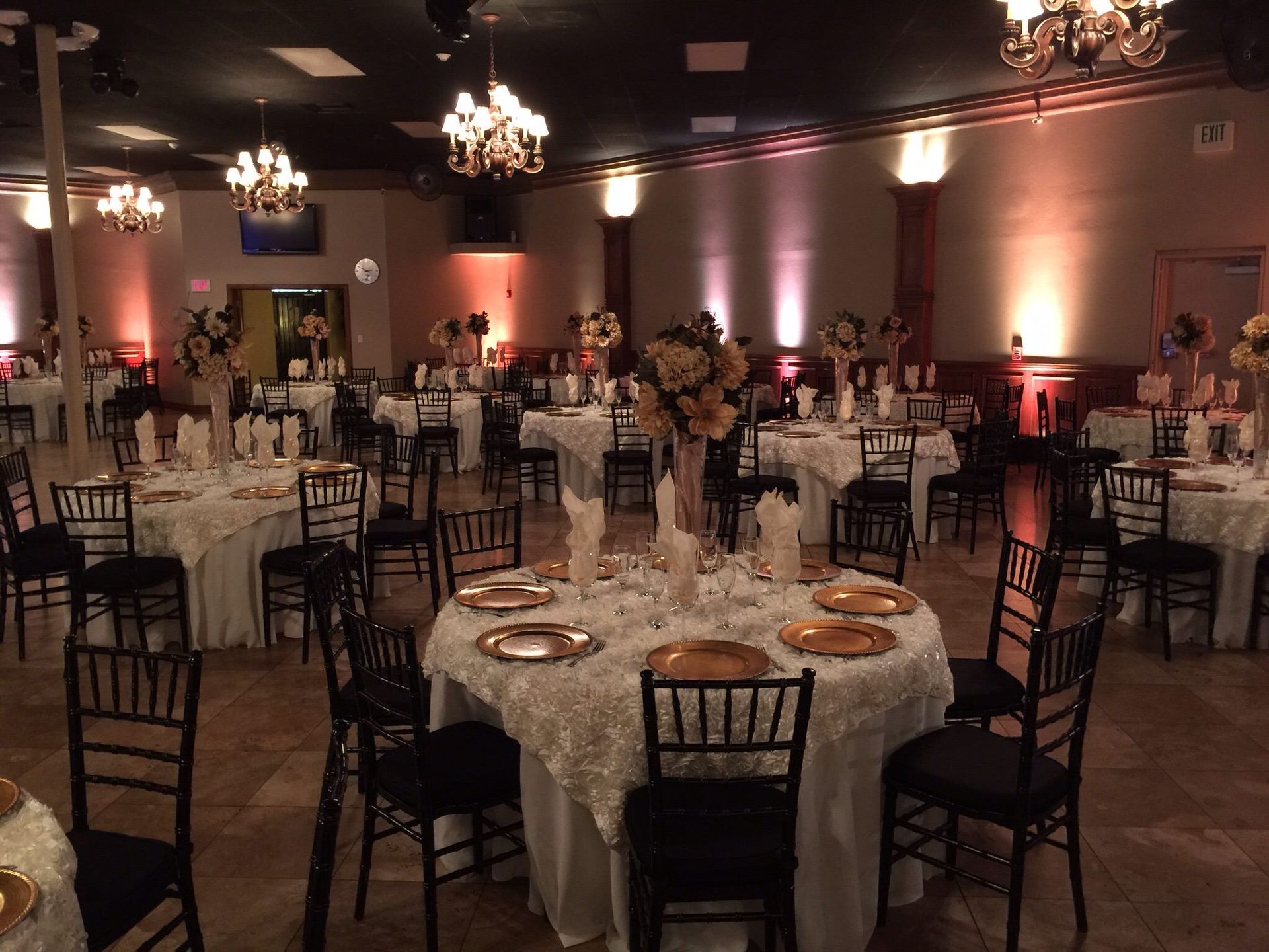 Banquet hall with round, candlelit tables and black chairs set for an event