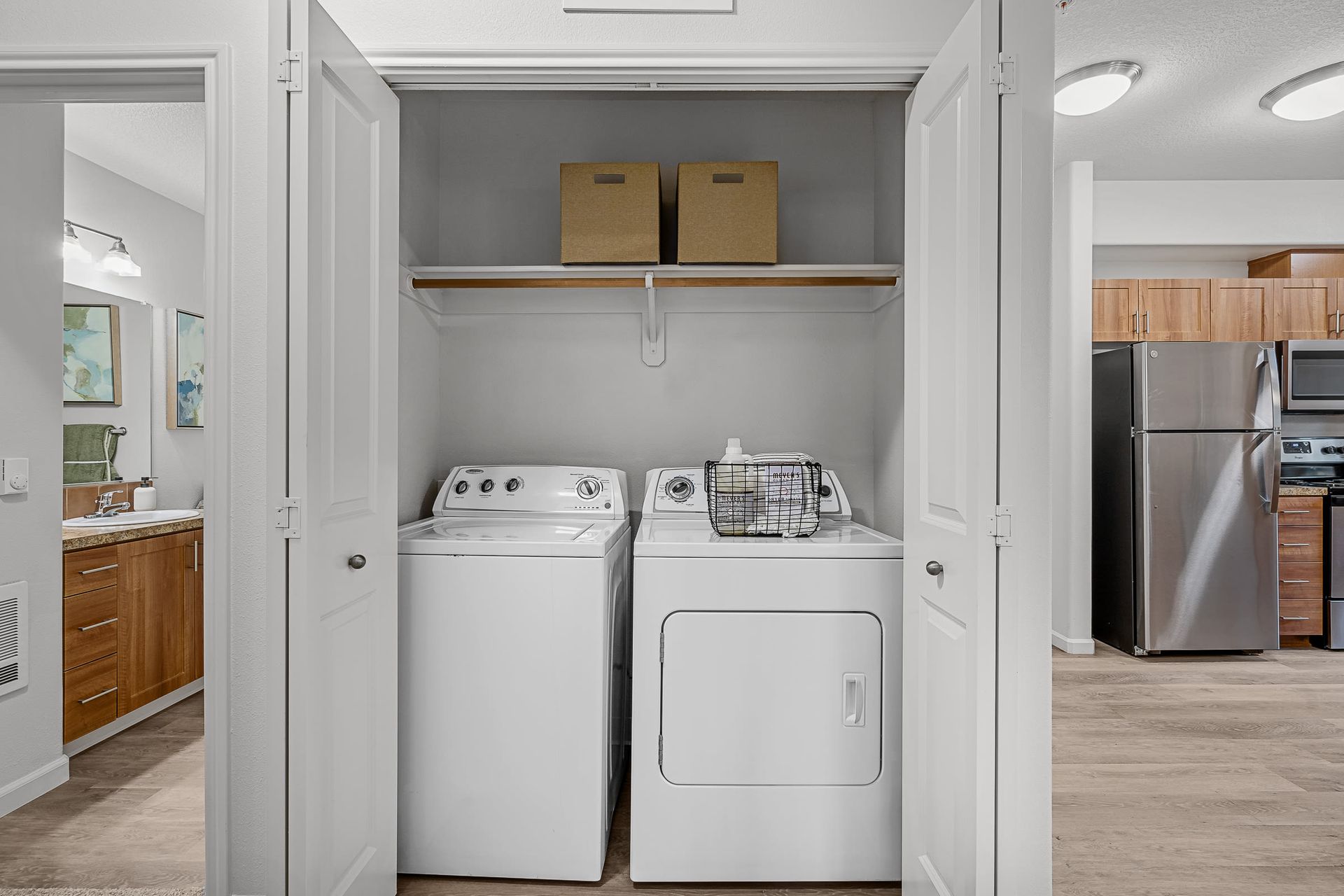 In-unit laundry closet with side-by-side washer and dryer and a shelf above.