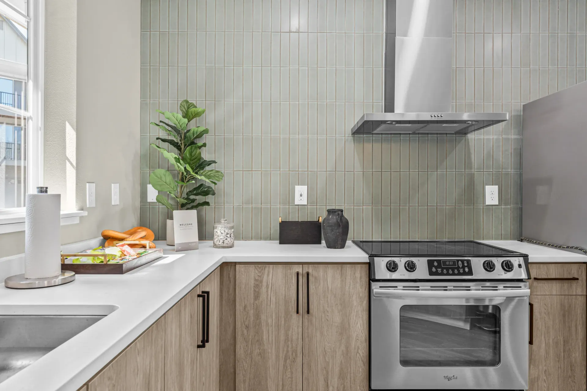 Kitchen with stainless steel stove, range hood, tiled backsplash, and wood-tone cabinets.