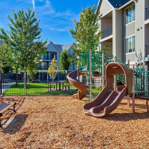 Playground with slides and a climbing structure in an apartment community courtyard.