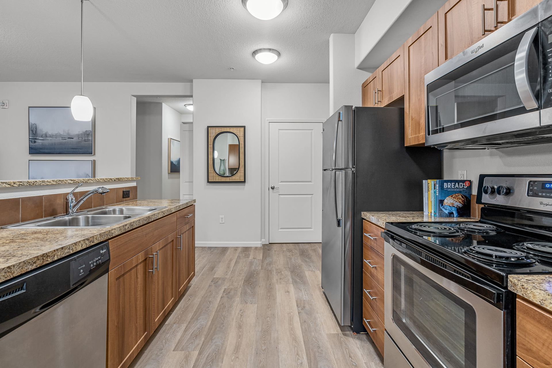 Kitchen in apartment with granite countertops, wooden cabinets, and stainless steel appliances.