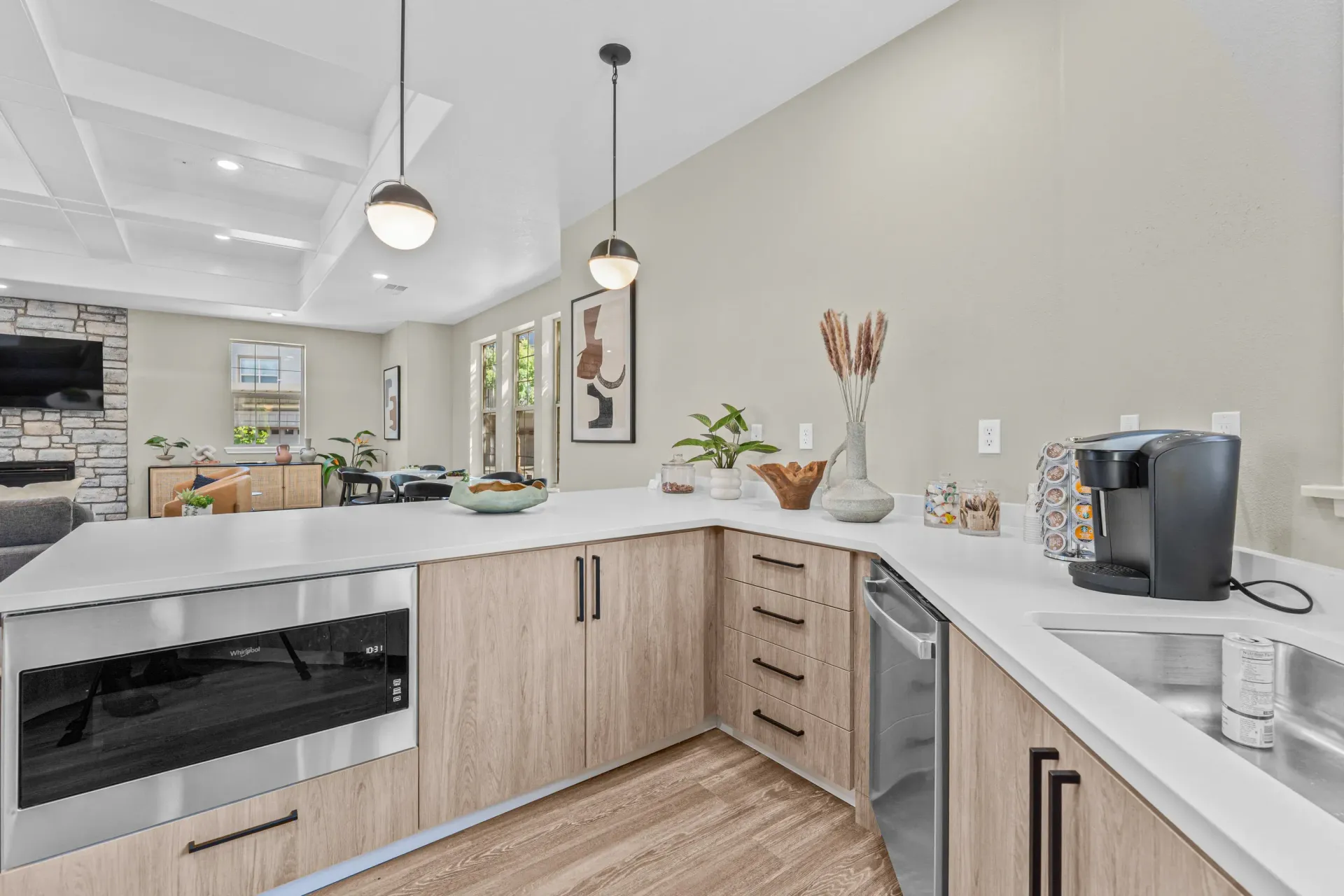 Open-concept kitchen with white countertops, light wood cabinetry, and stainless steel appliances.