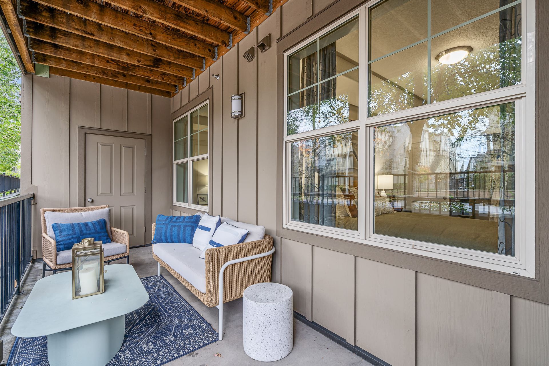 Covered balcony with wicker loveseat and chair, blue cushions, and a small coffee table.