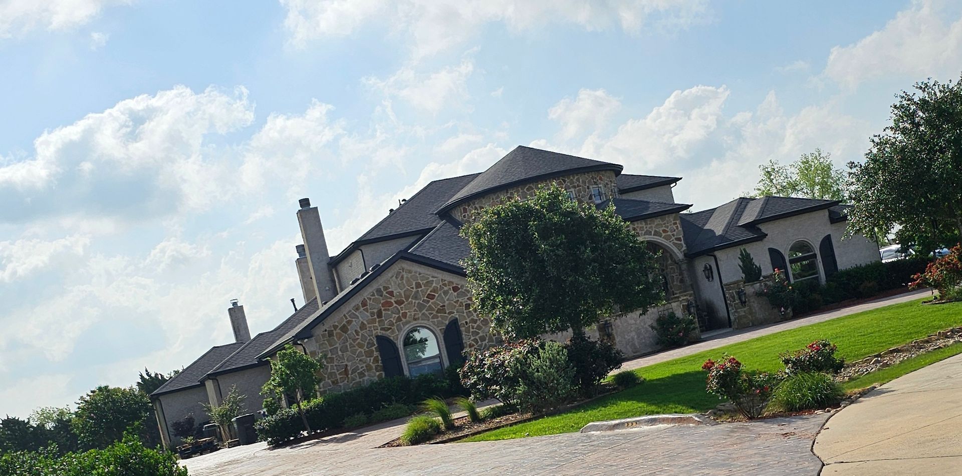 A large house is sitting on top of a lush green hillside.