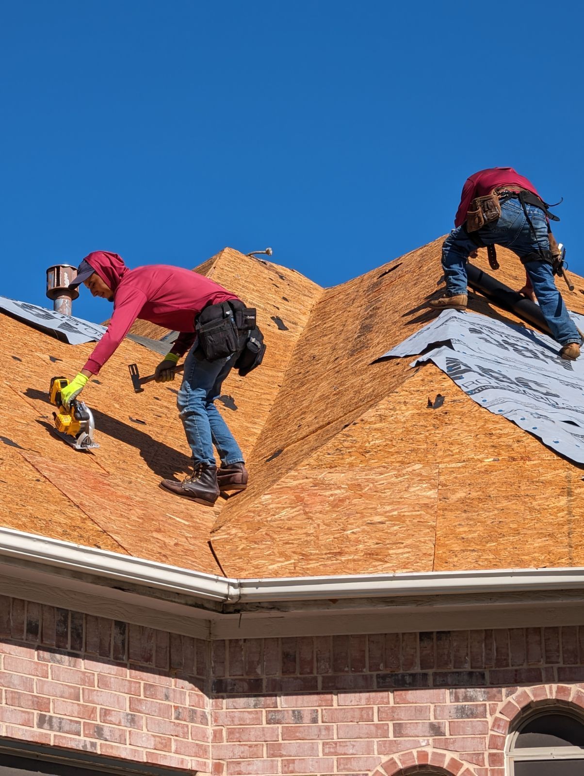Two men are working on the roof of a house.