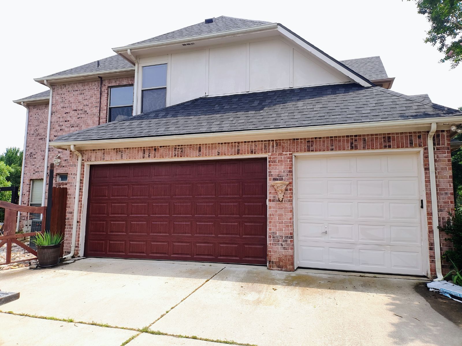 A large brick house with two garage doors and a roof.