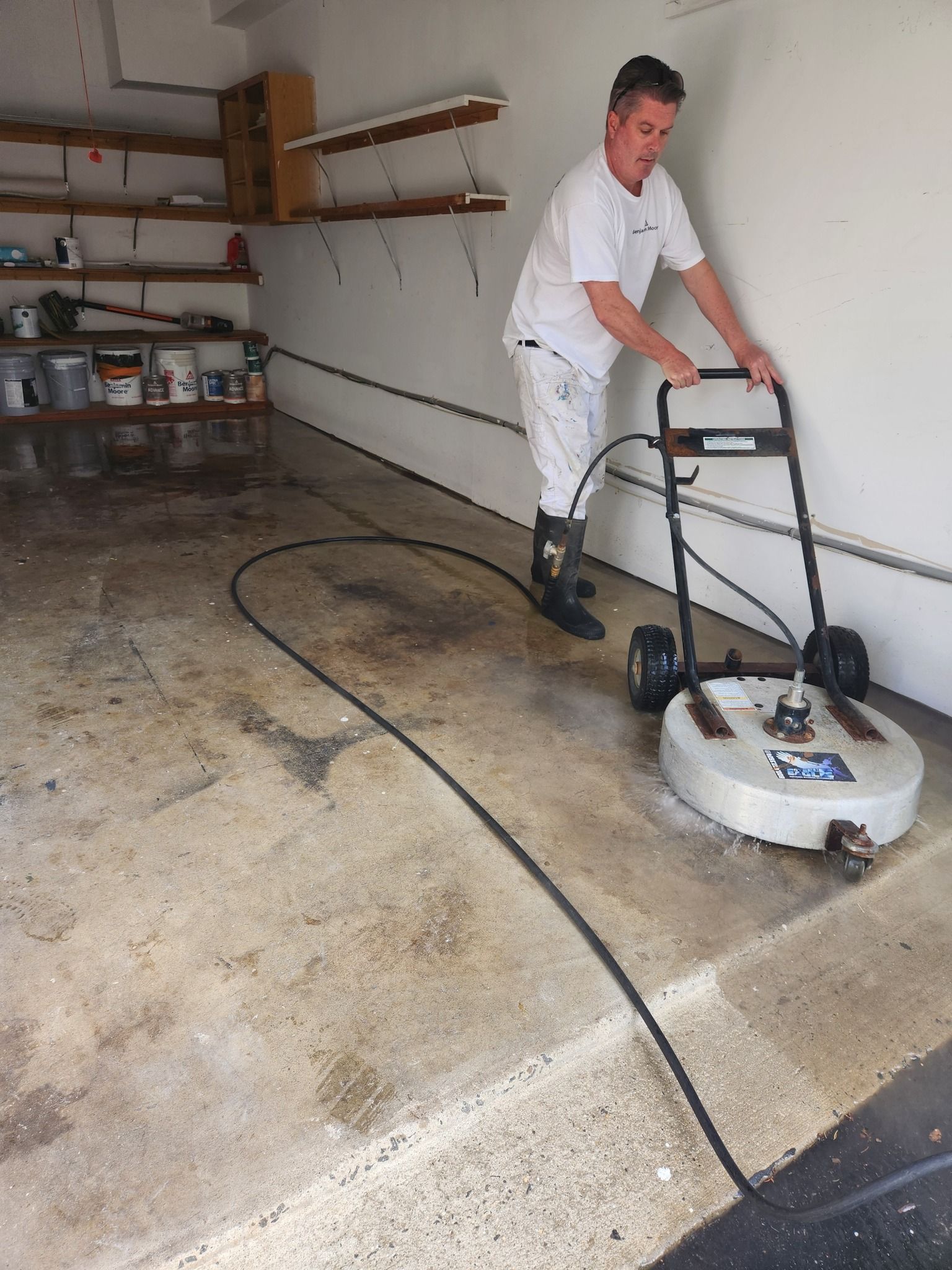 Man power washing a concrete garage floor.
