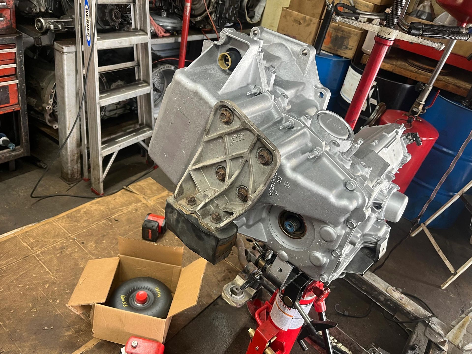 Engine block painted silver, mounted on a red engine stand in a cluttered garage setting.