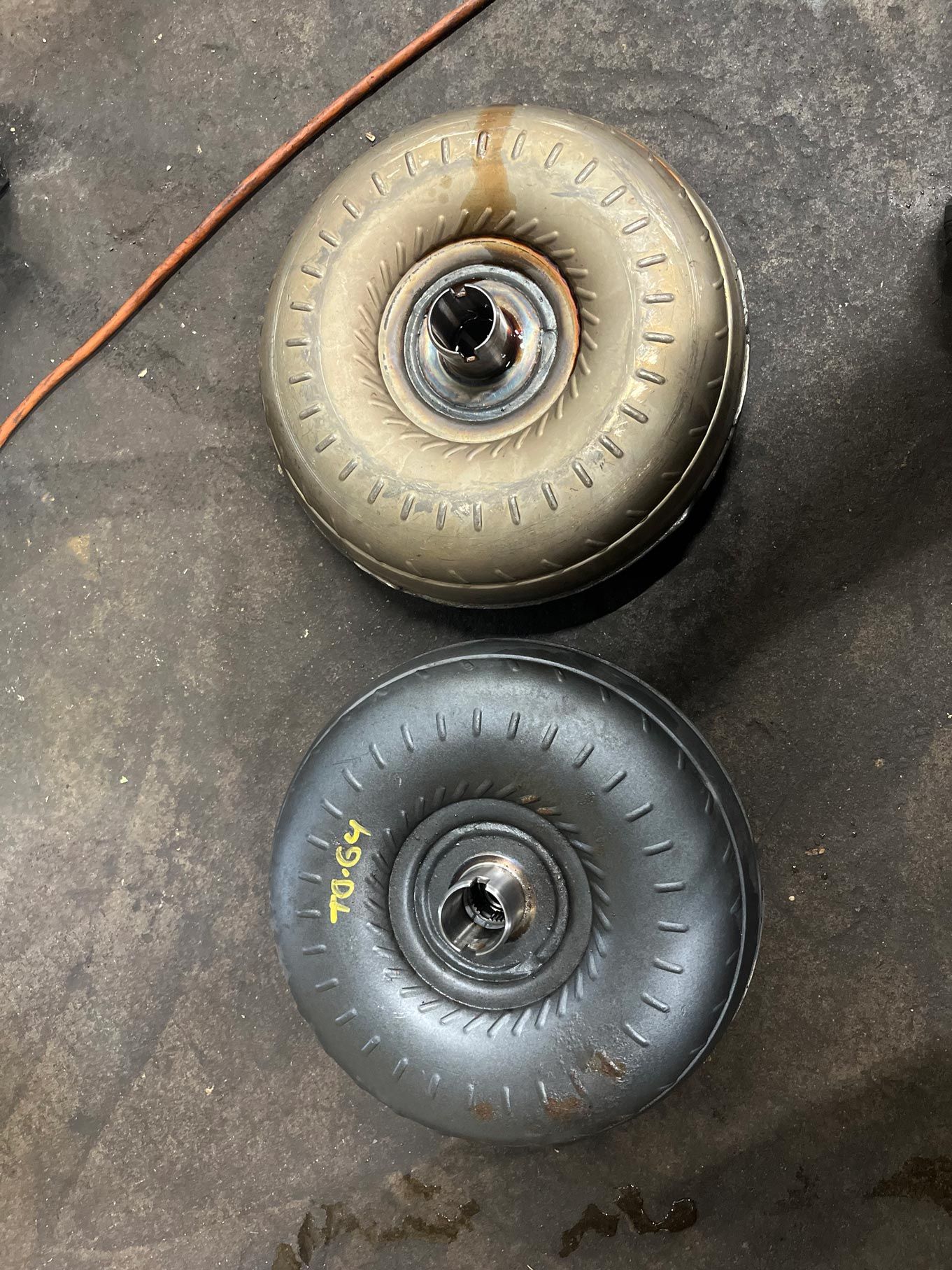 Two automotive torque converters: one worn and lighter, one new and black.