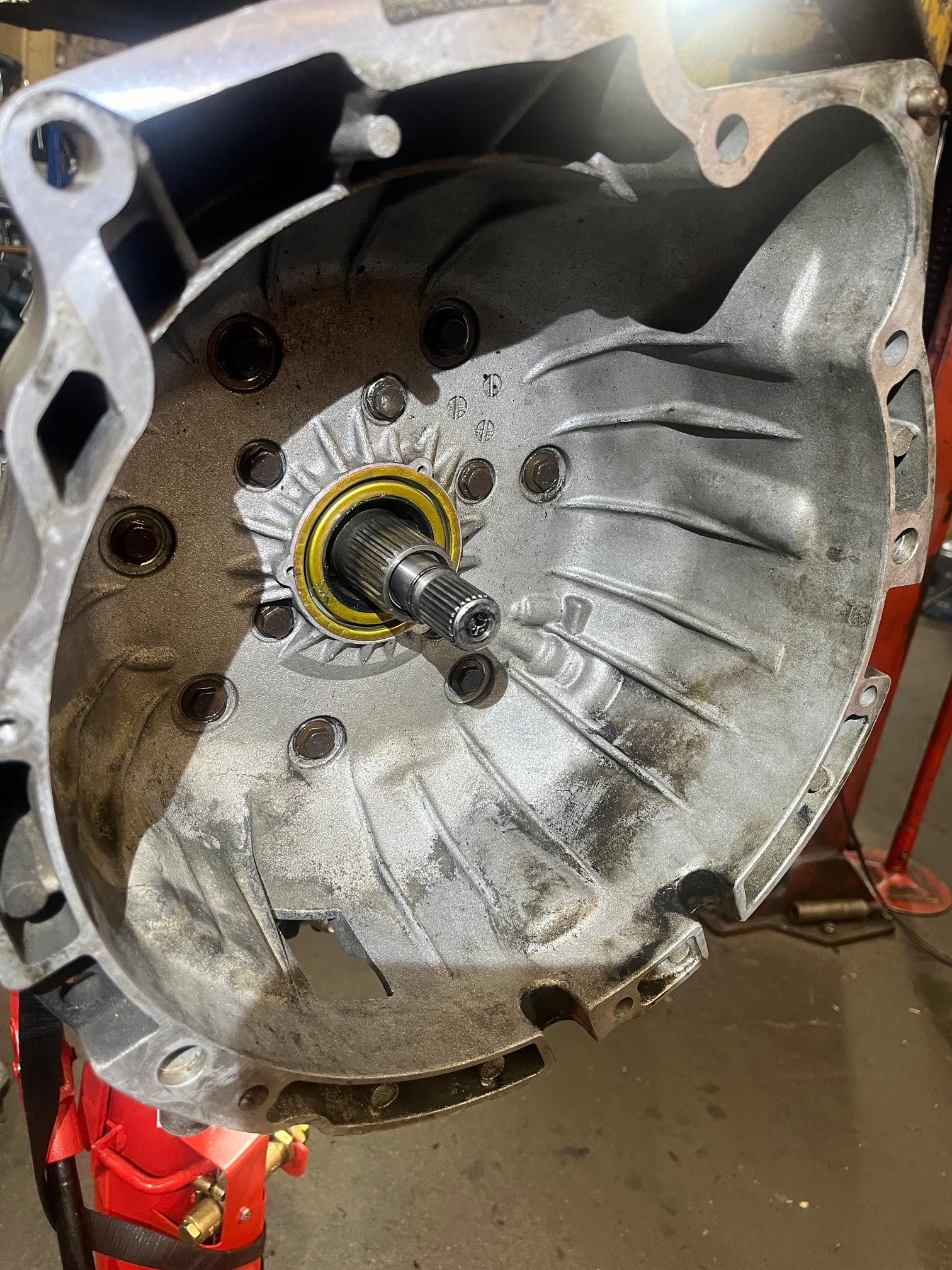 Inside of a car's transmission case. A shaft is in the center. Black bolts are visible.