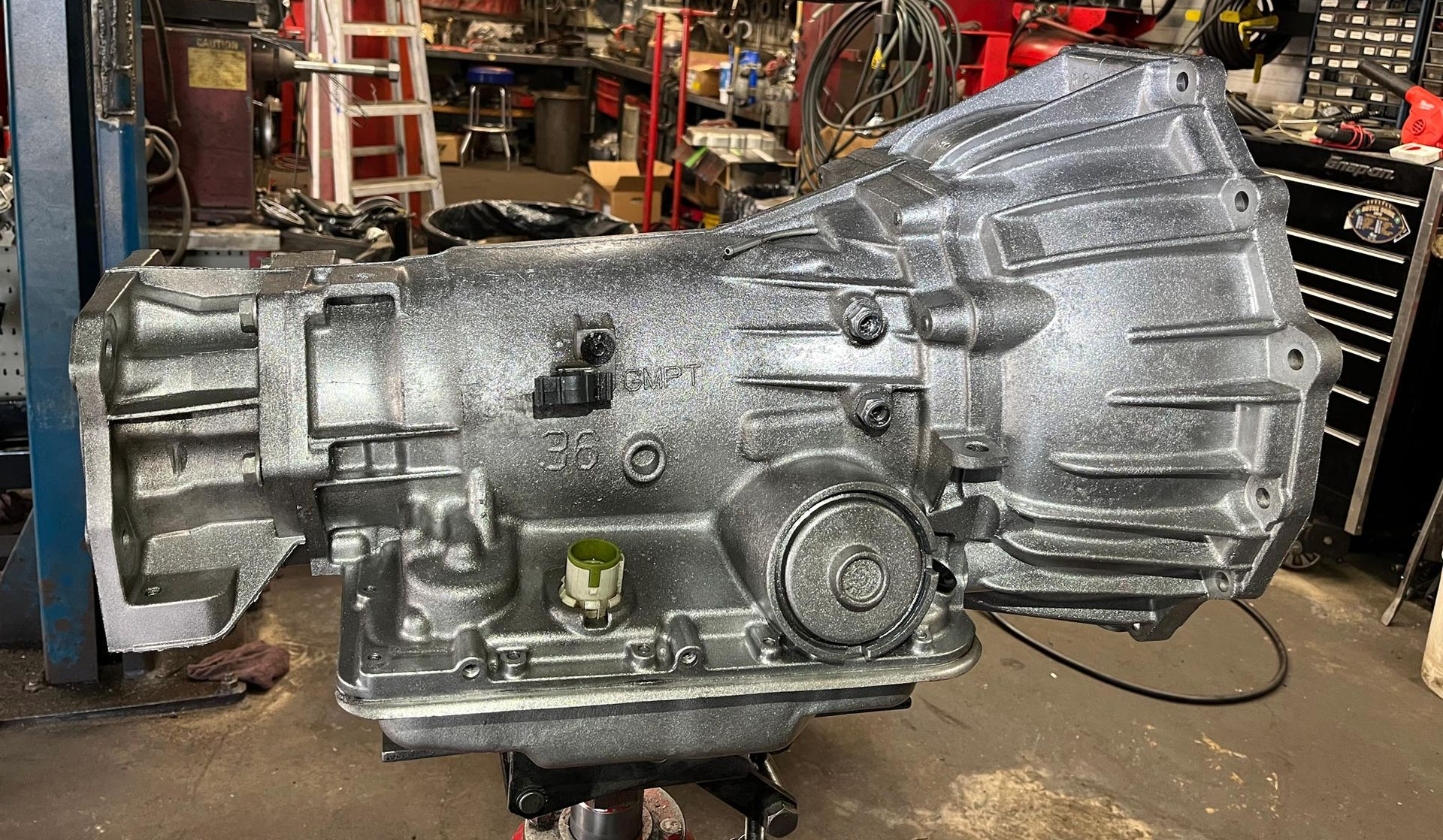 Black oil pan under a vehicle, visible with a drive shaft and tubing.