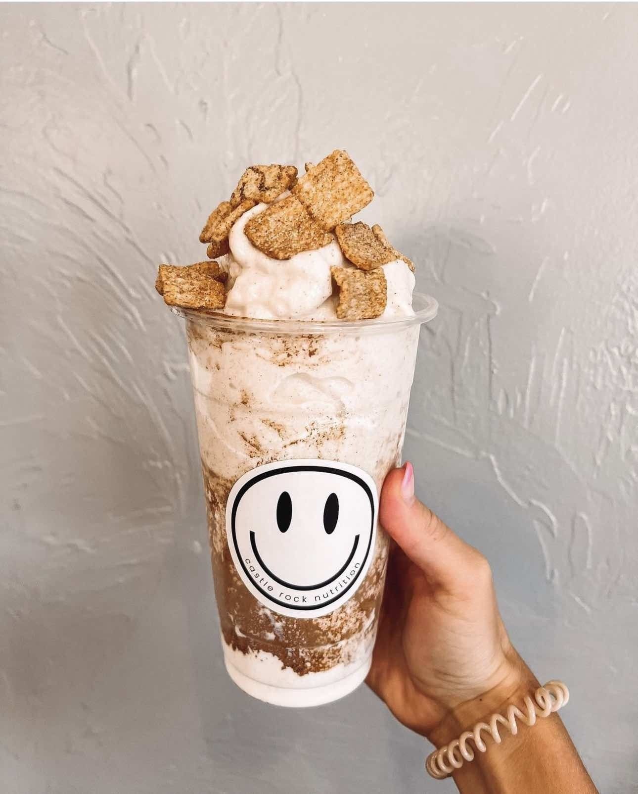 A person is holding a cup with a smiley face on it