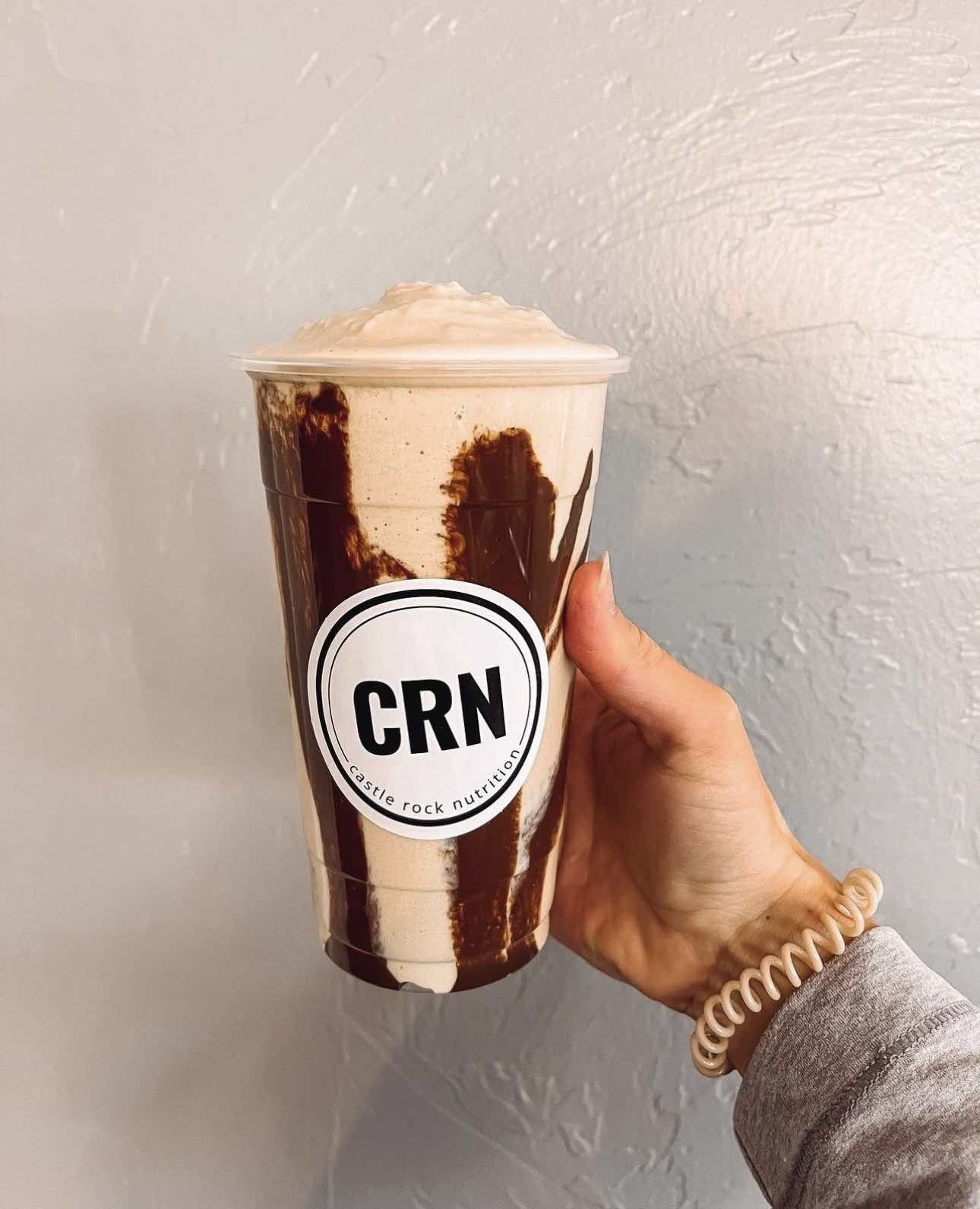 A person is holding a cup of coffee with a crn sticker on it.