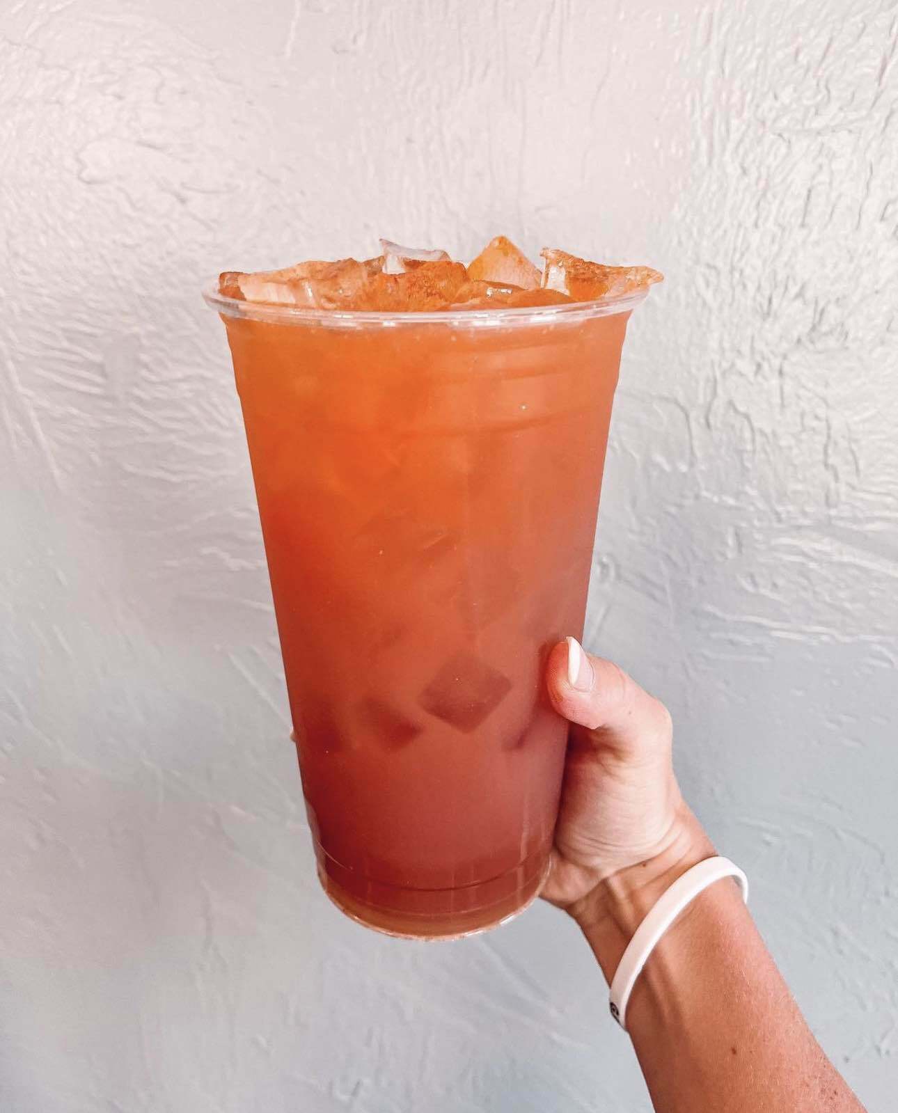 A person is holding a cup of iced tea in their hand.