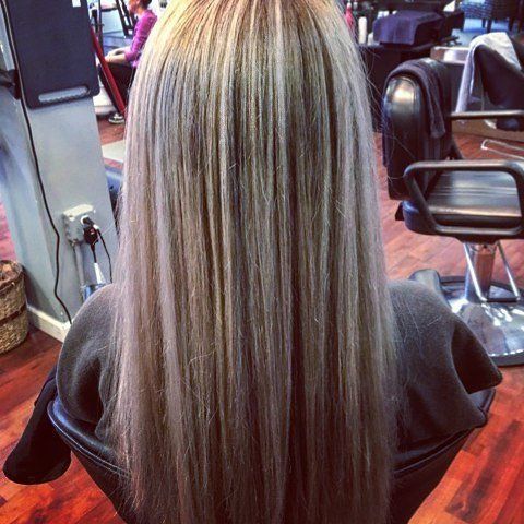 A woman with long blonde hair is sitting in a chair in a salon.