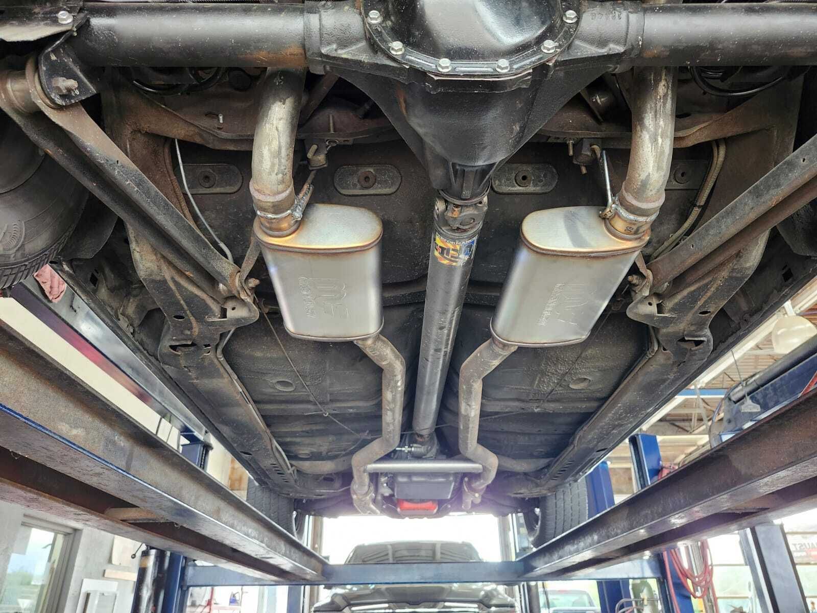 Undercarriage of a vehicle showing exhaust system, suspension, and rear axle. Vehicle is on a lift.| Garbs Automotive & Exhaust