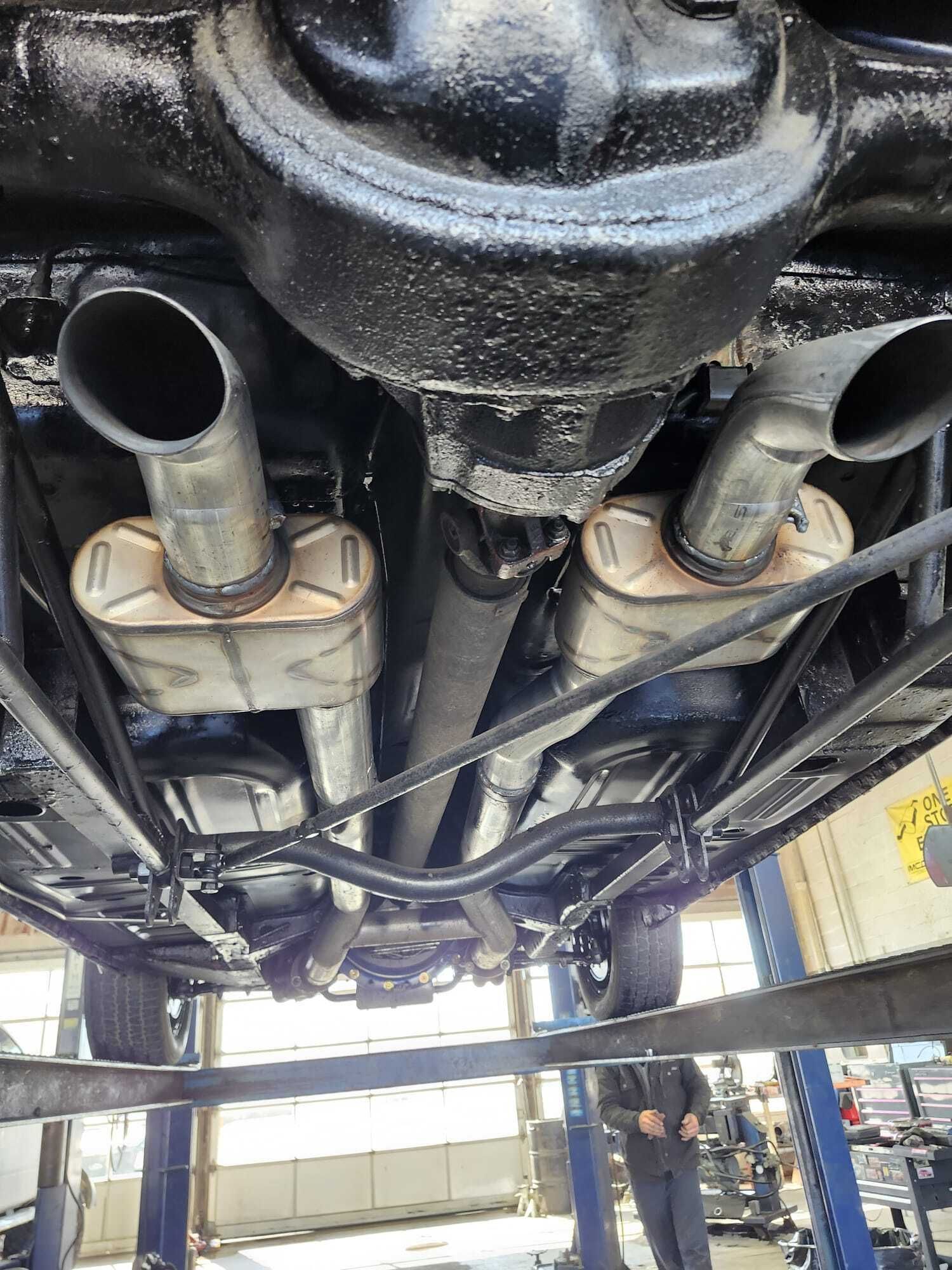 Undercarriage of a vehicle, showing exhaust system, mufflers, and drive shaft. Vehicle is elevated on a lift.| Garbs Automotive & Exhaust