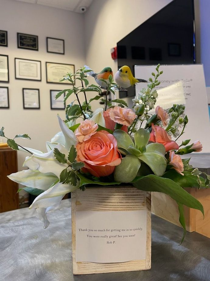 Flower arrangement with peach roses and greenery in a white box on a table in an office lobby