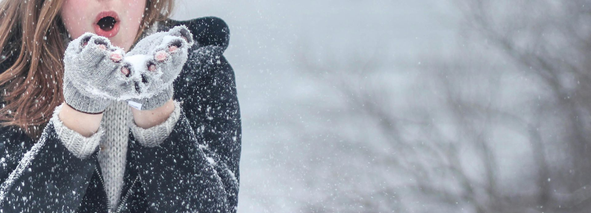 Woman blowing snow from her hands