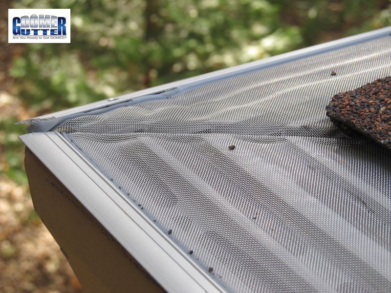 A person is installing a gutter on the side of a house.