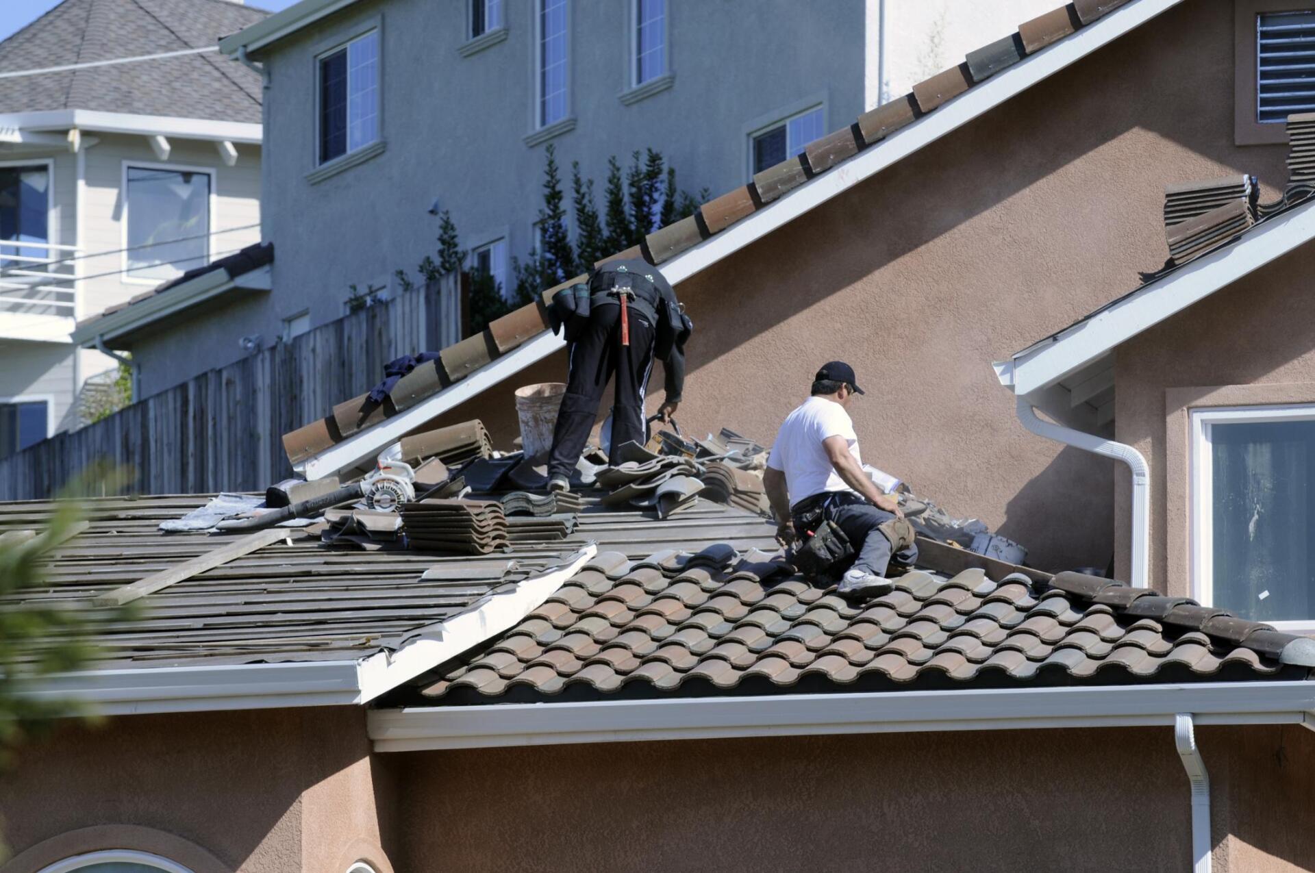 two roofers working on top of roof