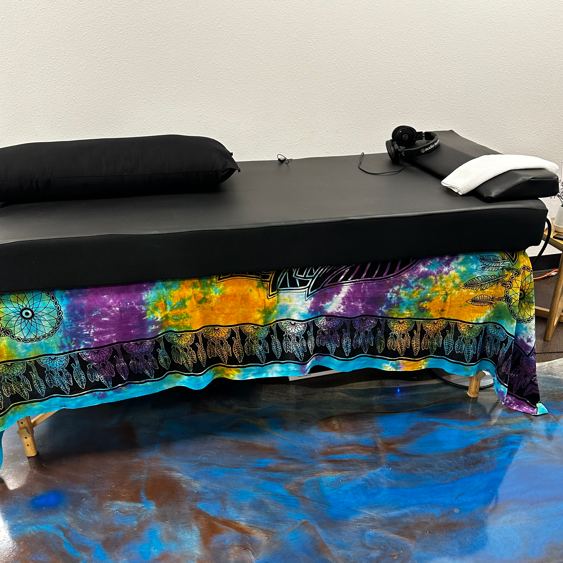 A massage table with a tie dye cloth on it