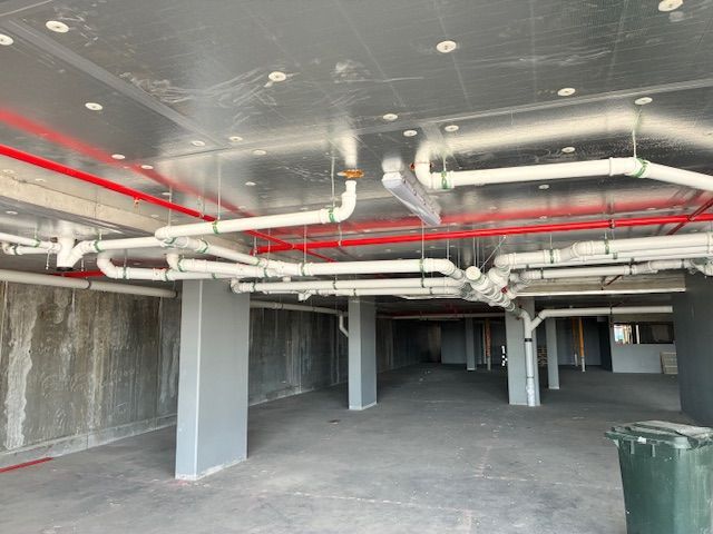 Plumber working on copper pipes with a wrench and adjusting a valve near a pressure gauge.