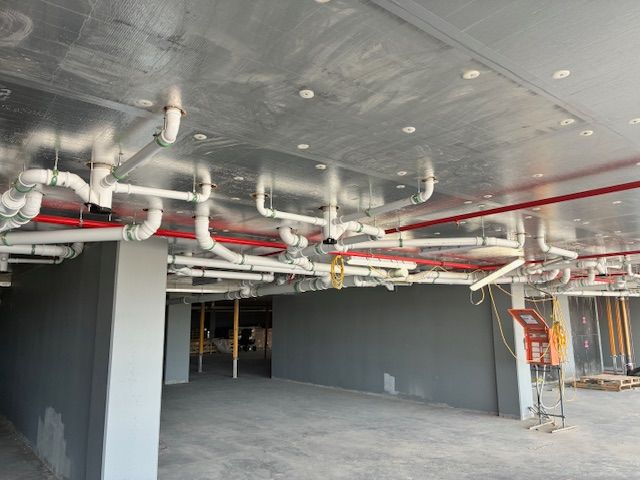 Plumber working on copper pipes with a wrench and adjusting a valve near a pressure gauge.