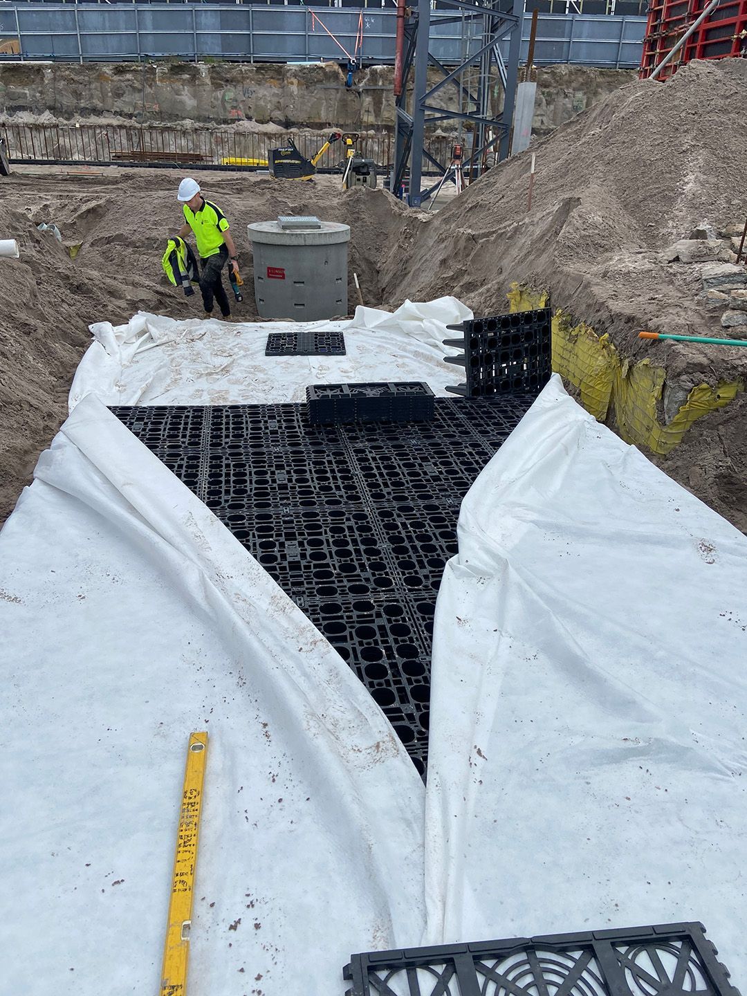 Plumber in gloves working on white and gray pipes, checking valves in a tiled room.