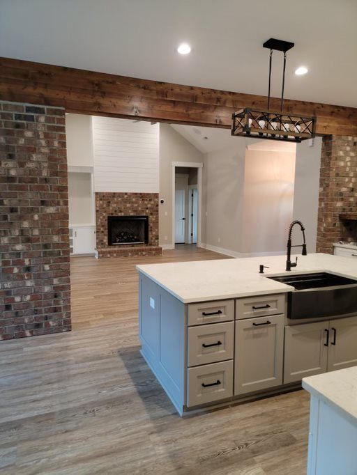 A kitchen with a sink and a fireplace in the background
