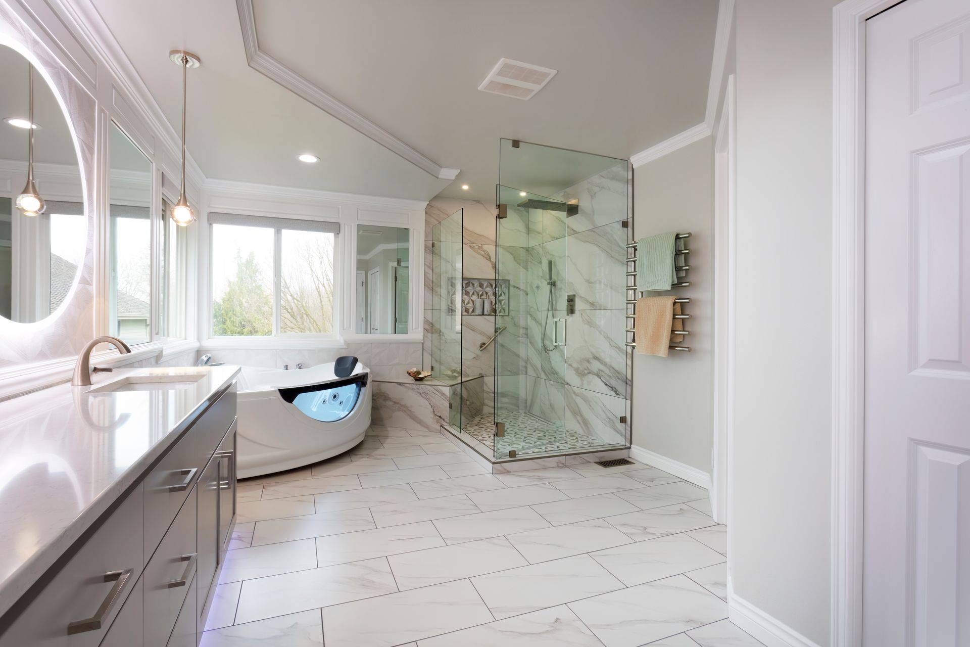 Spacious, modern bathroom with white and gray accents. Features a shower, tub, vanity, and large window.