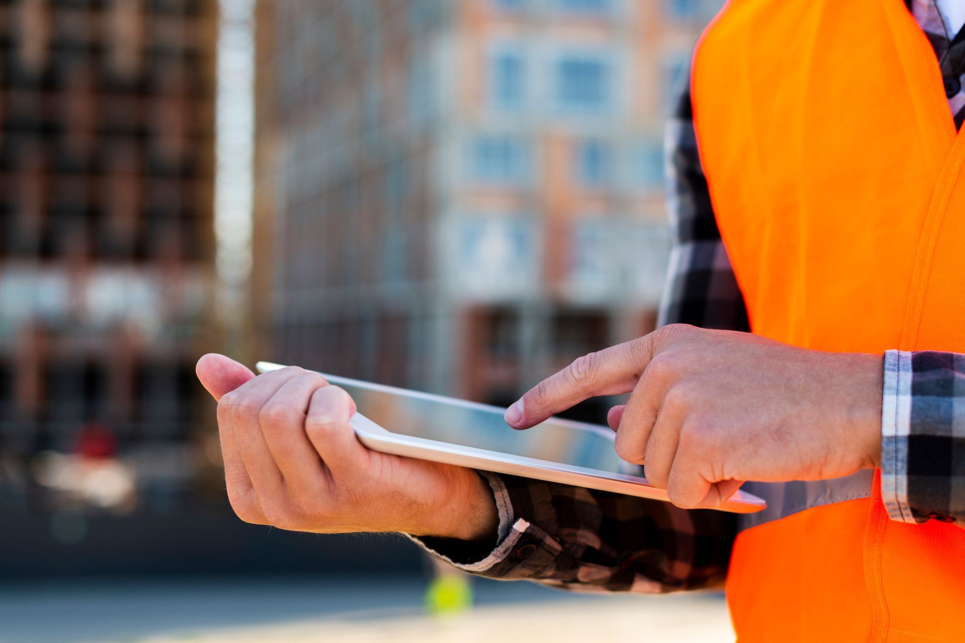 A construction worker is using a tablet computer on a construction site.