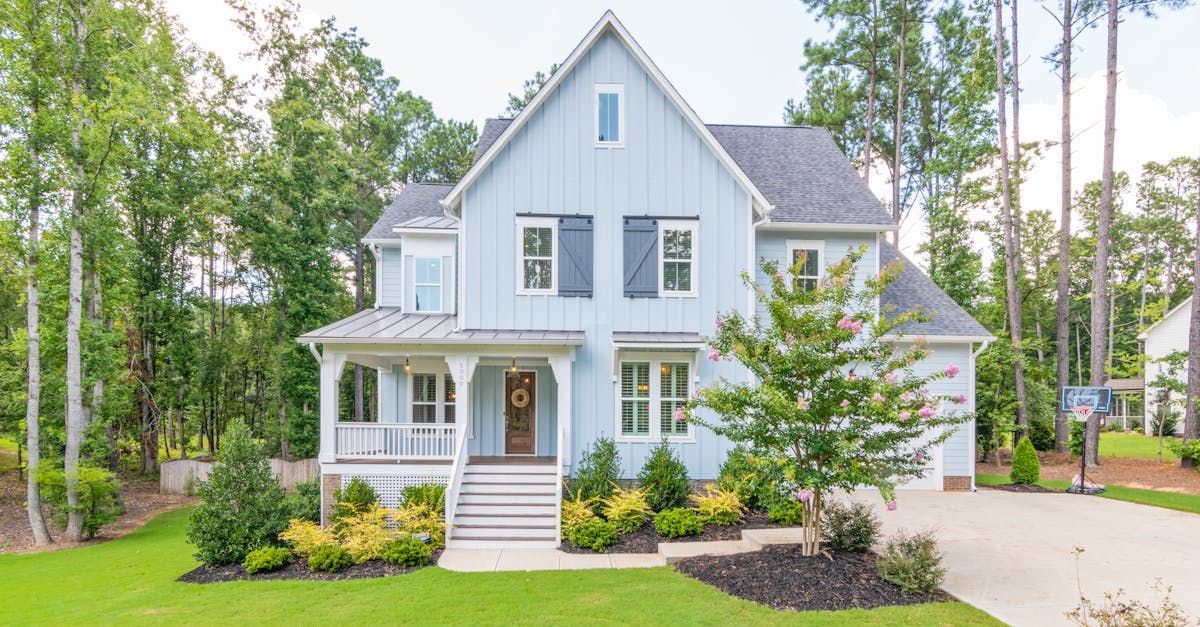 A large blue house with a lot of windows and trees in the background.