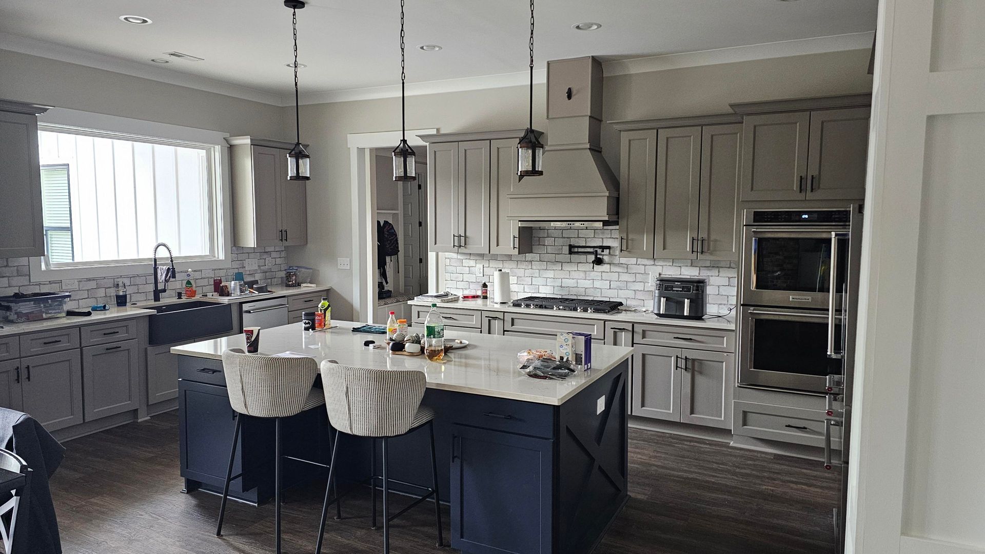 Kitchen with gray cabinets, a navy blue island, stainless steel appliances, and white countertops.