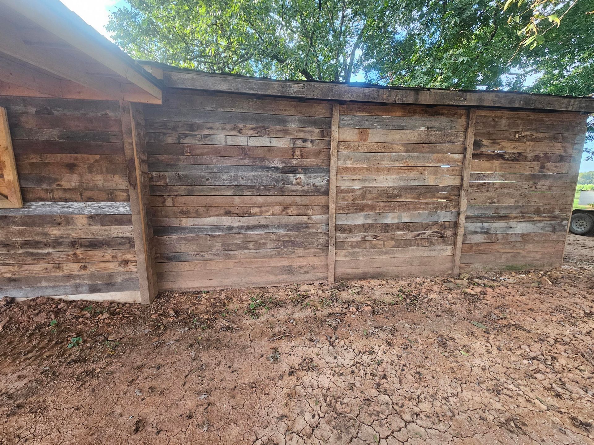 Wooden shed with horizontal planks, built on bare earth. Brown and grey tones.