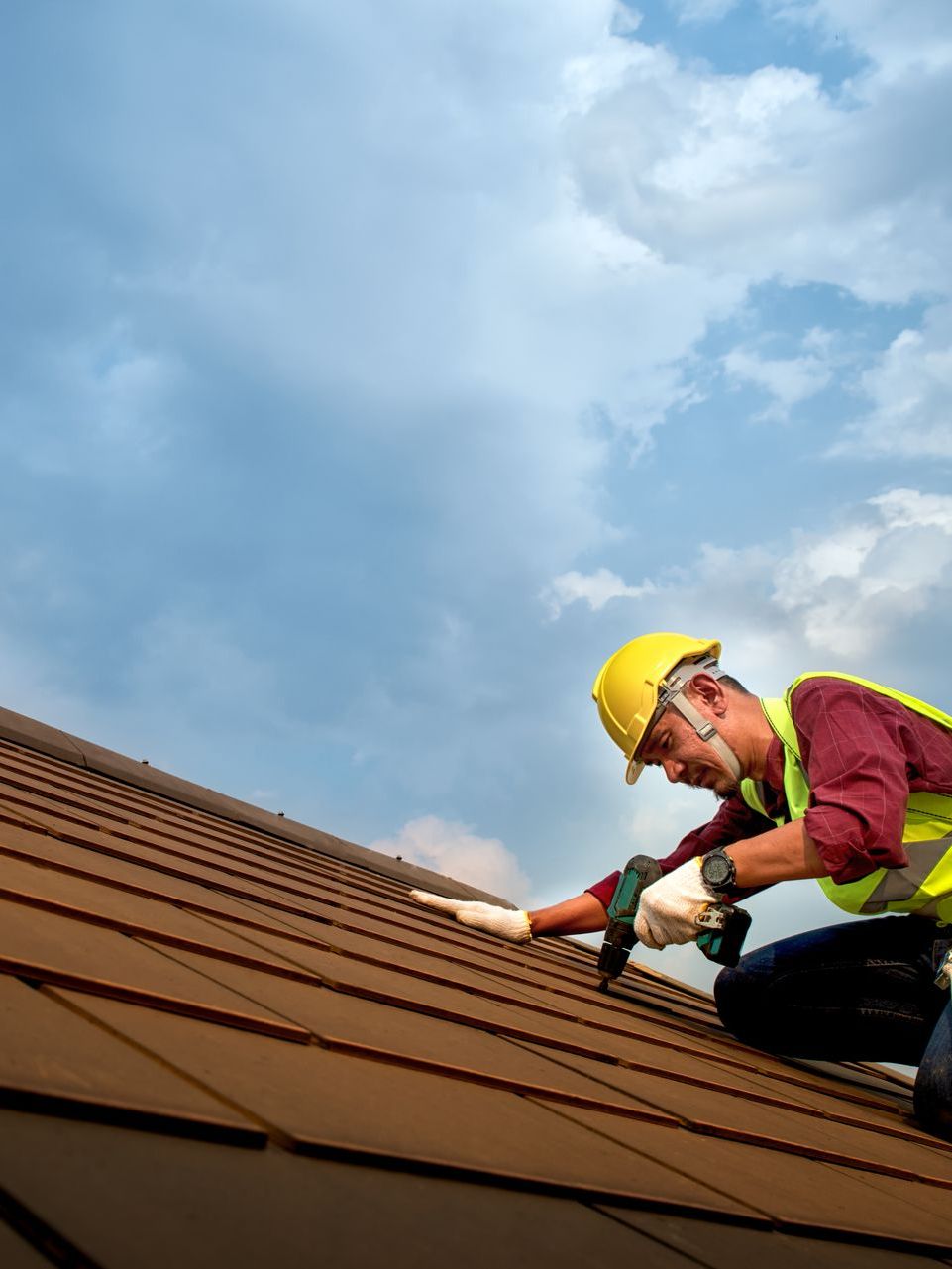 A man wearing a hard hat is working on a roof