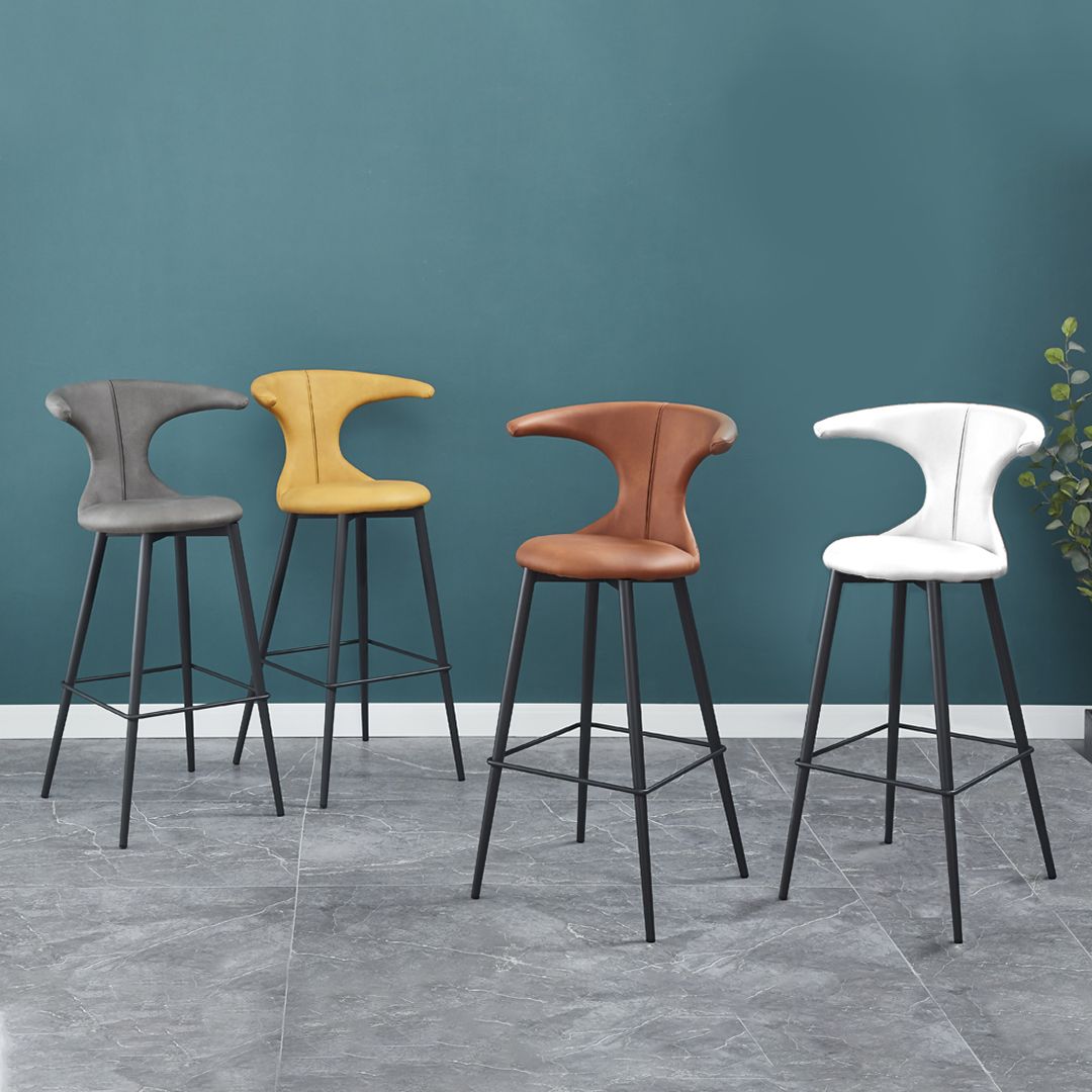 Four bar stools are lined up in a row in front of a blue wall.