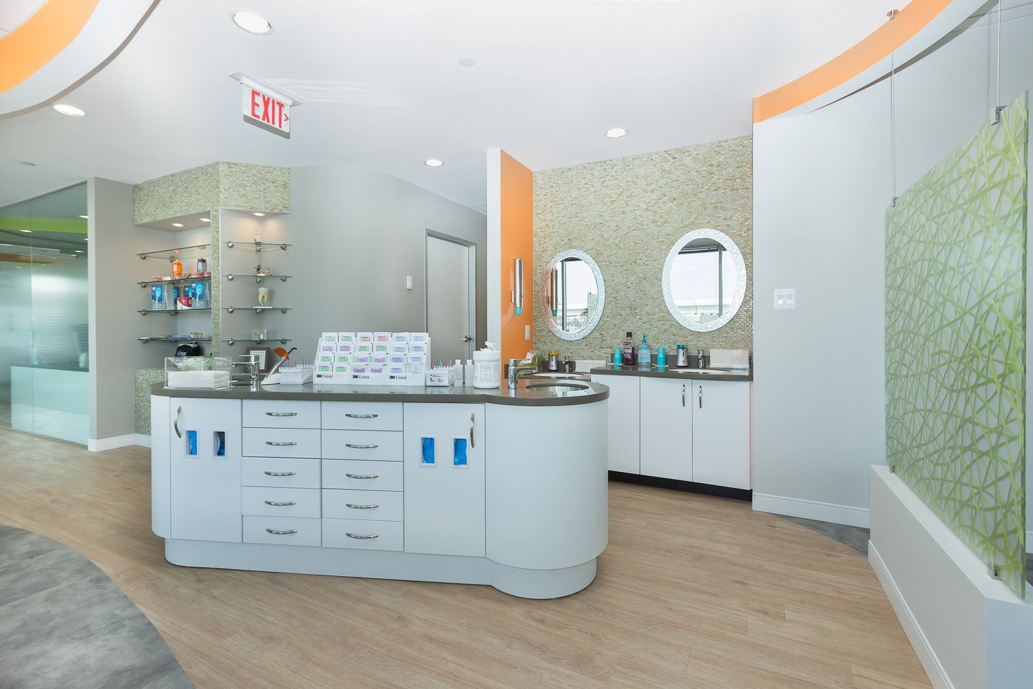 Modern dental office reception area with curved white desk, sinks, and decorative tile.