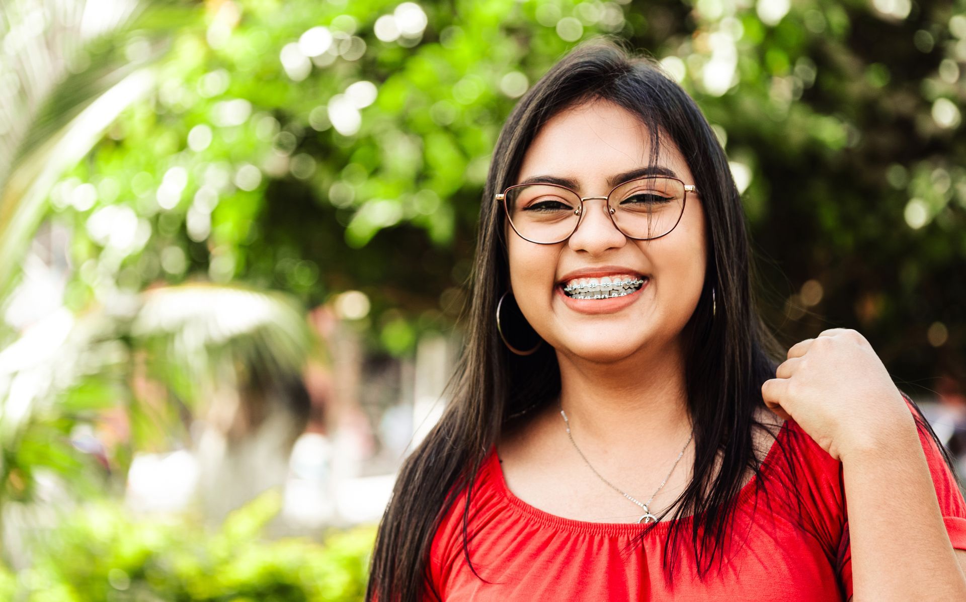 A young woman wearing glasses and braces is smiling for the camera.