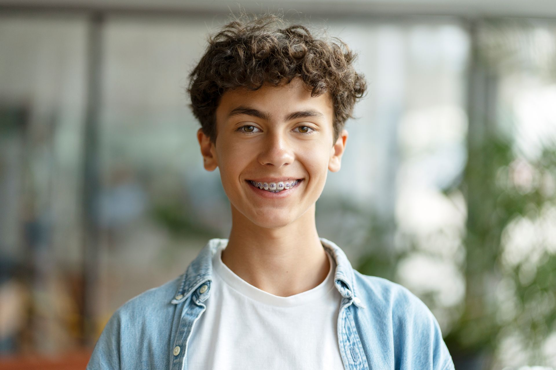 A young man with braces on his teeth is smiling.