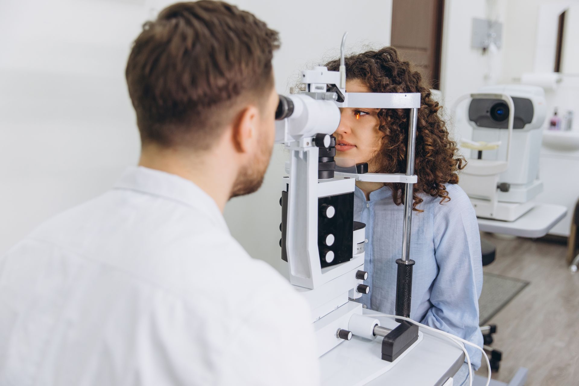 An optometrist examining a patient's eyes using a slit lamp during a comprehensive vision checkup.