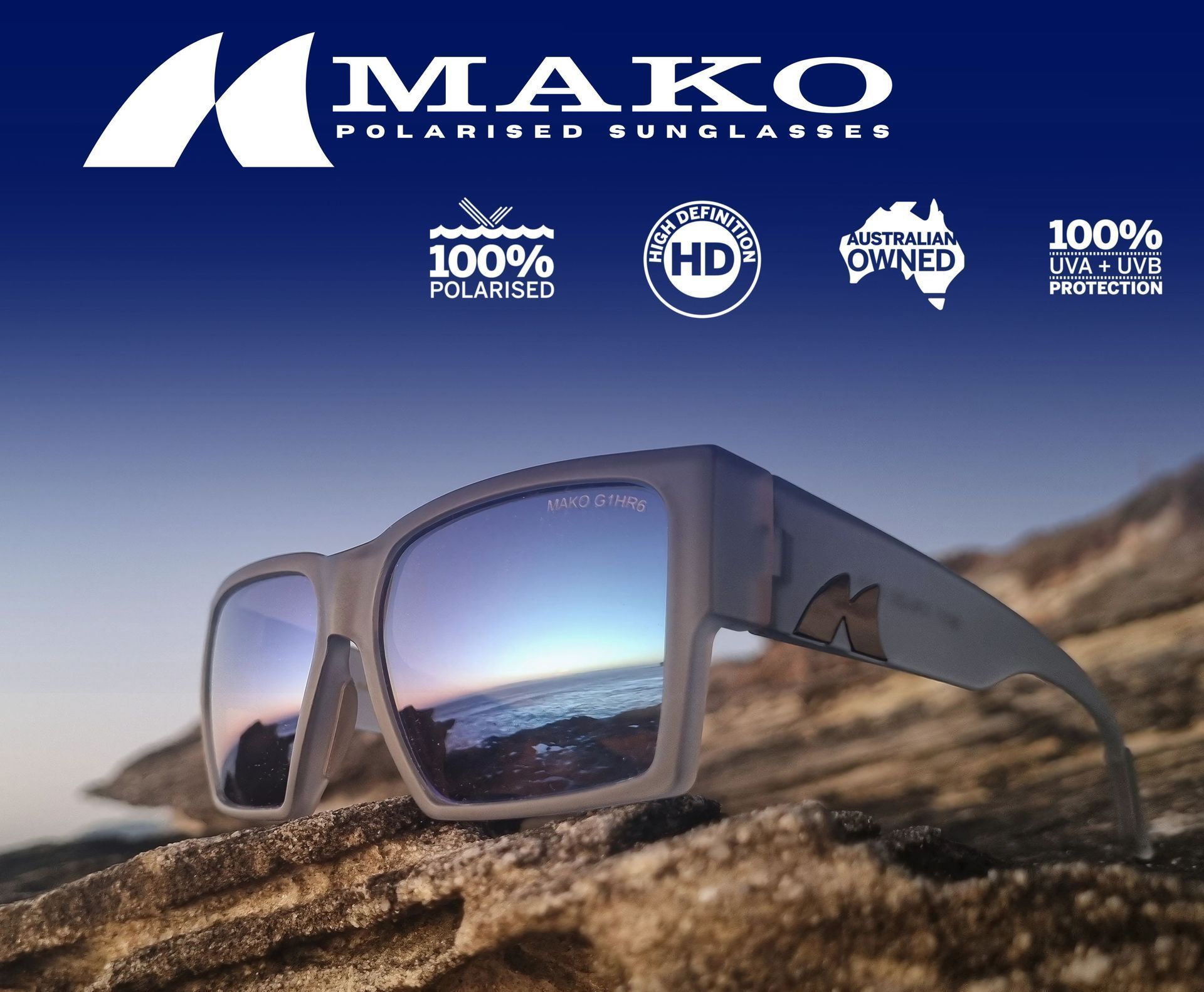 Mako polarized sunglasses with mirror lenses resting on a rocky shore under the brand logo and icons.