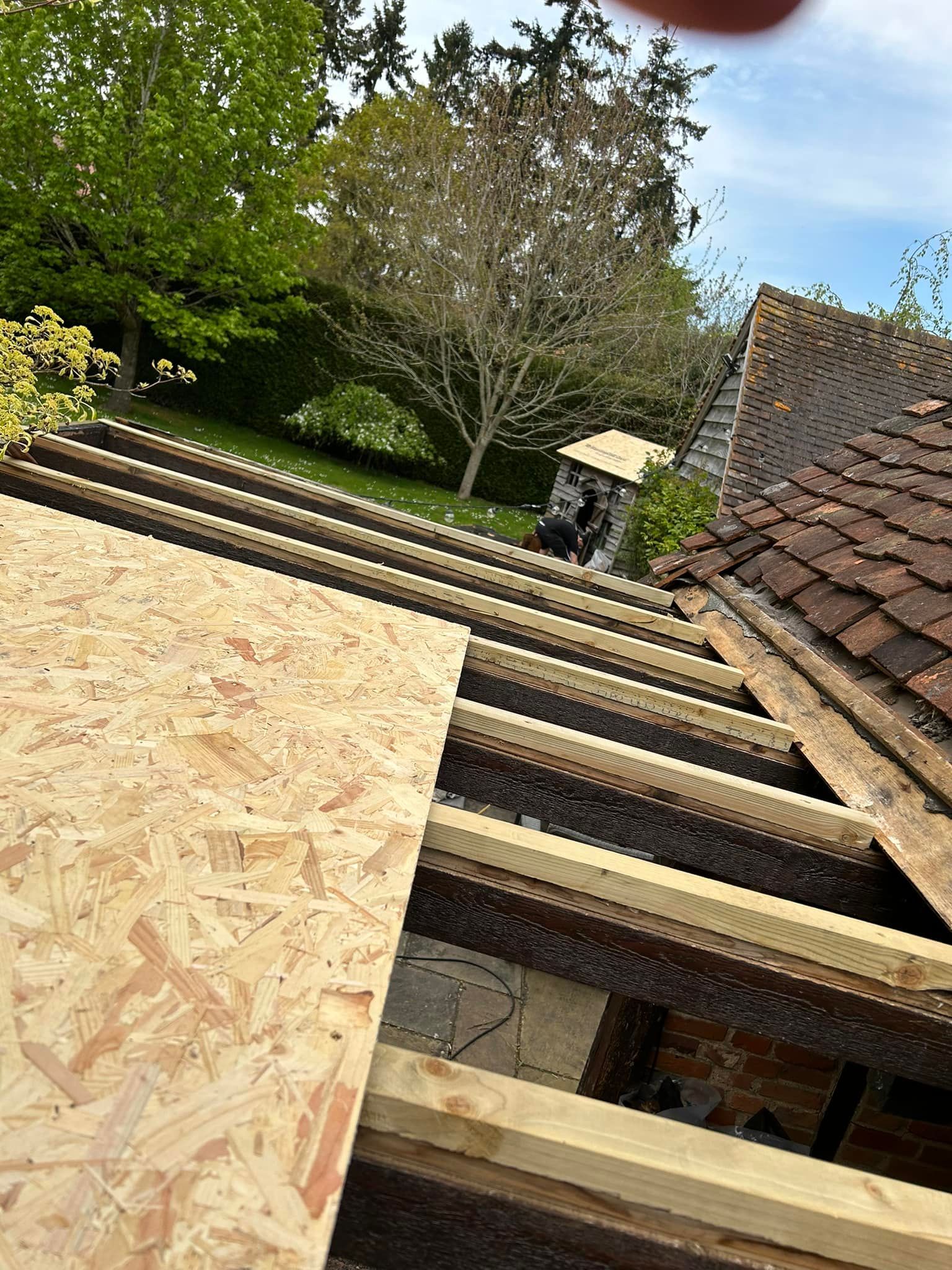 A person is holding a piece of plywood on top of a roof.