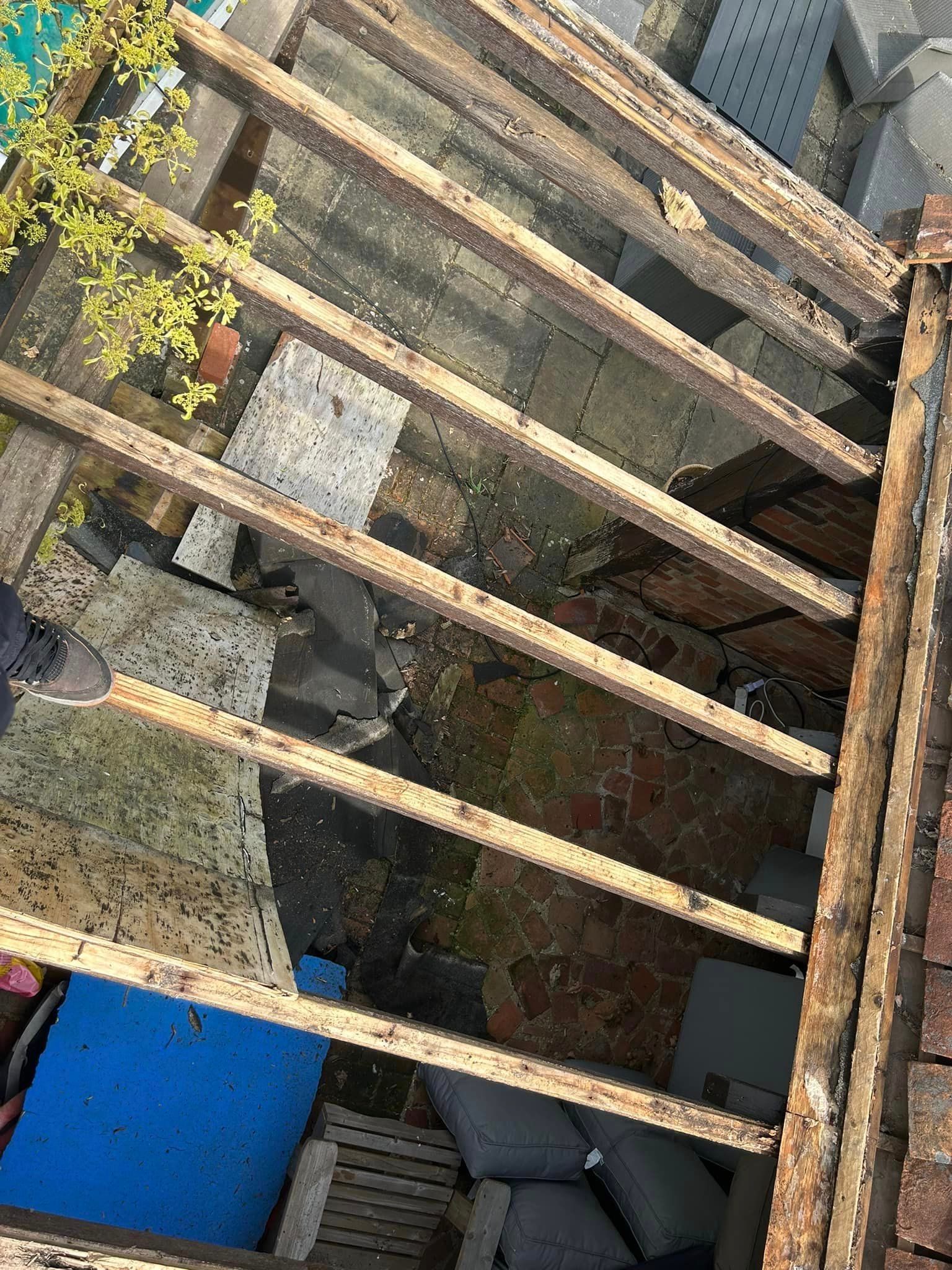 A person is looking down at a roof with wooden beams.