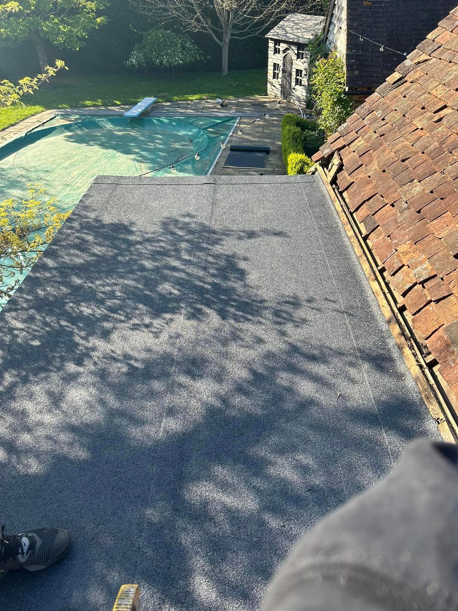 A person is standing on a flat felt roof.