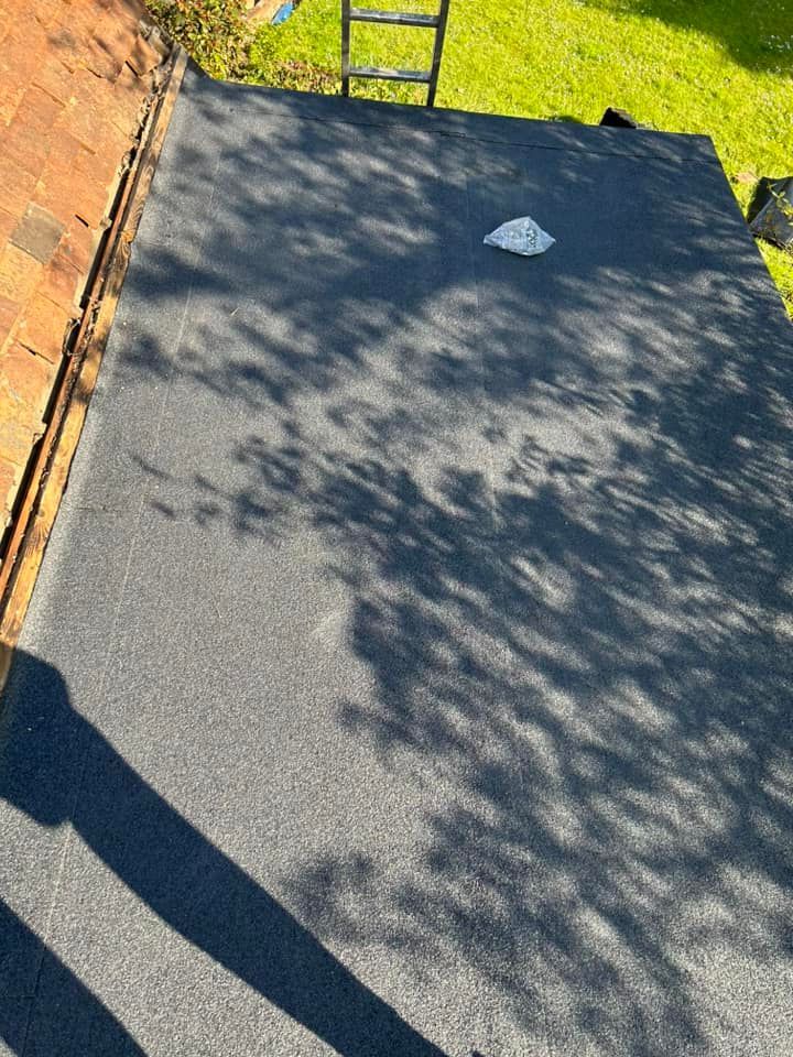 A black roof with a ladder sitting on top of it.