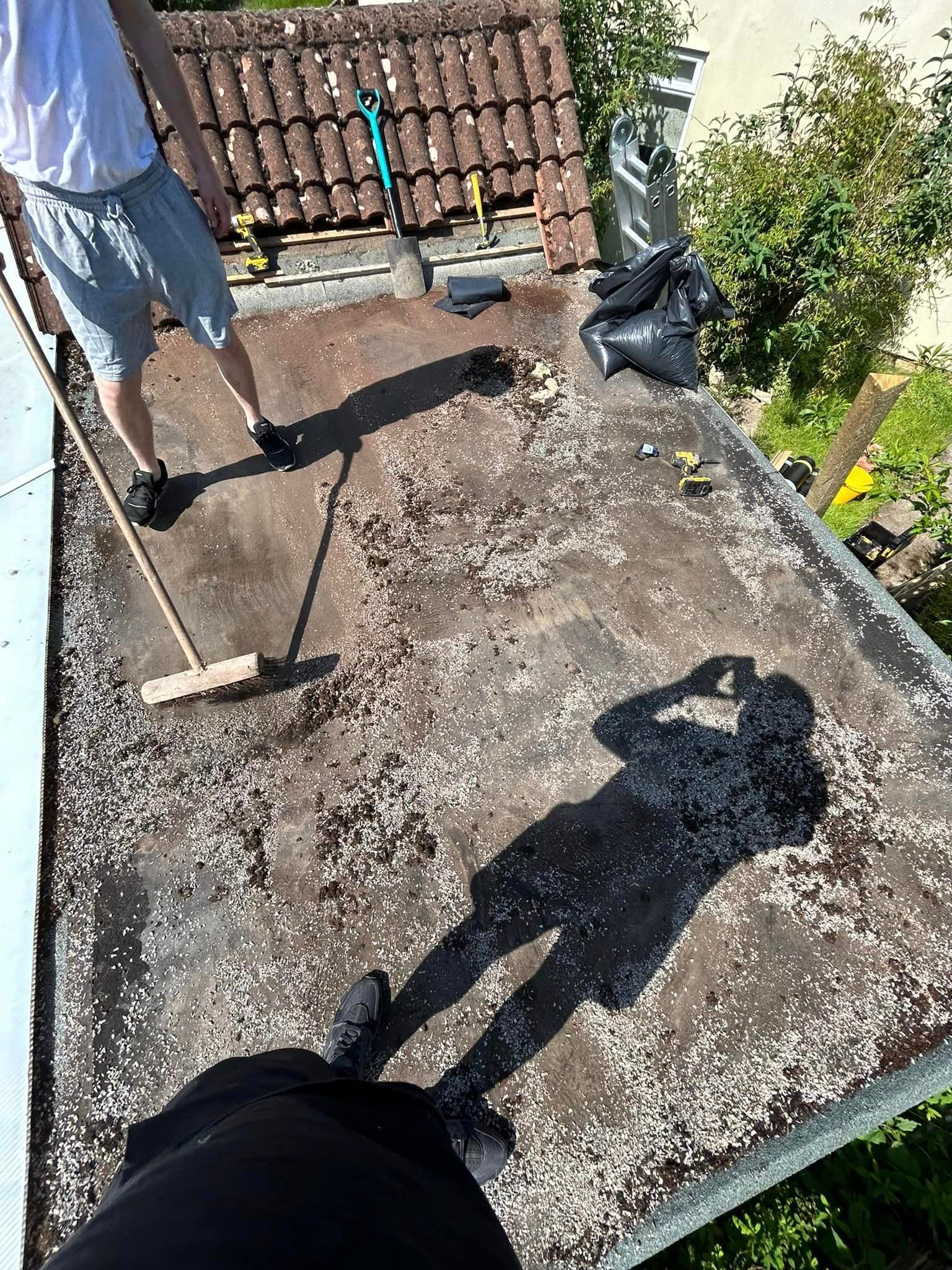 A man is sweeping the roof of a building with a broom.