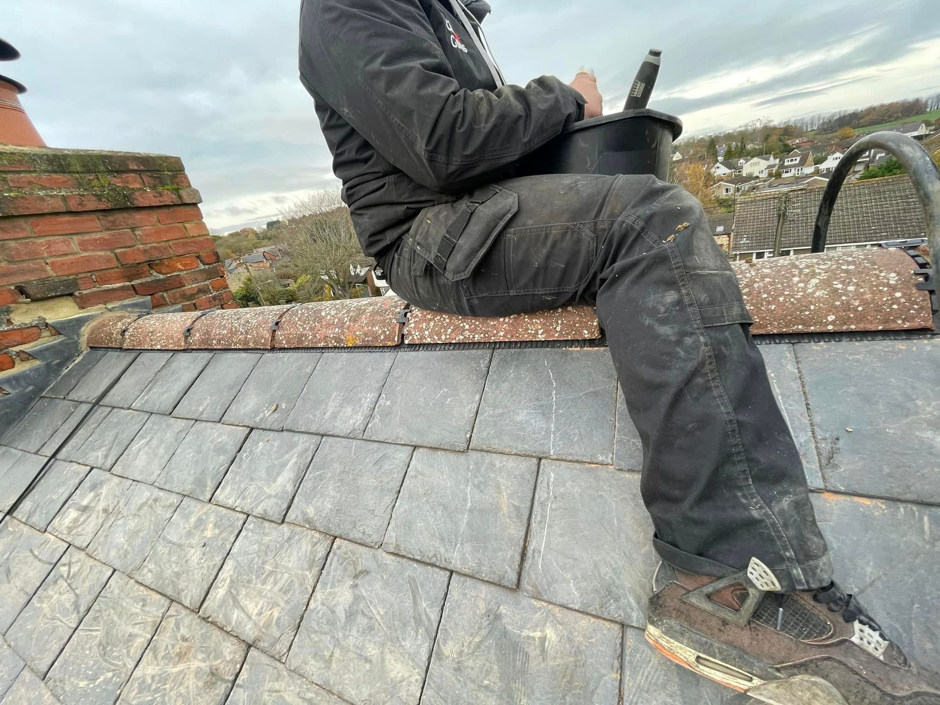 A roofer is repairing roof ridges on a slate roof