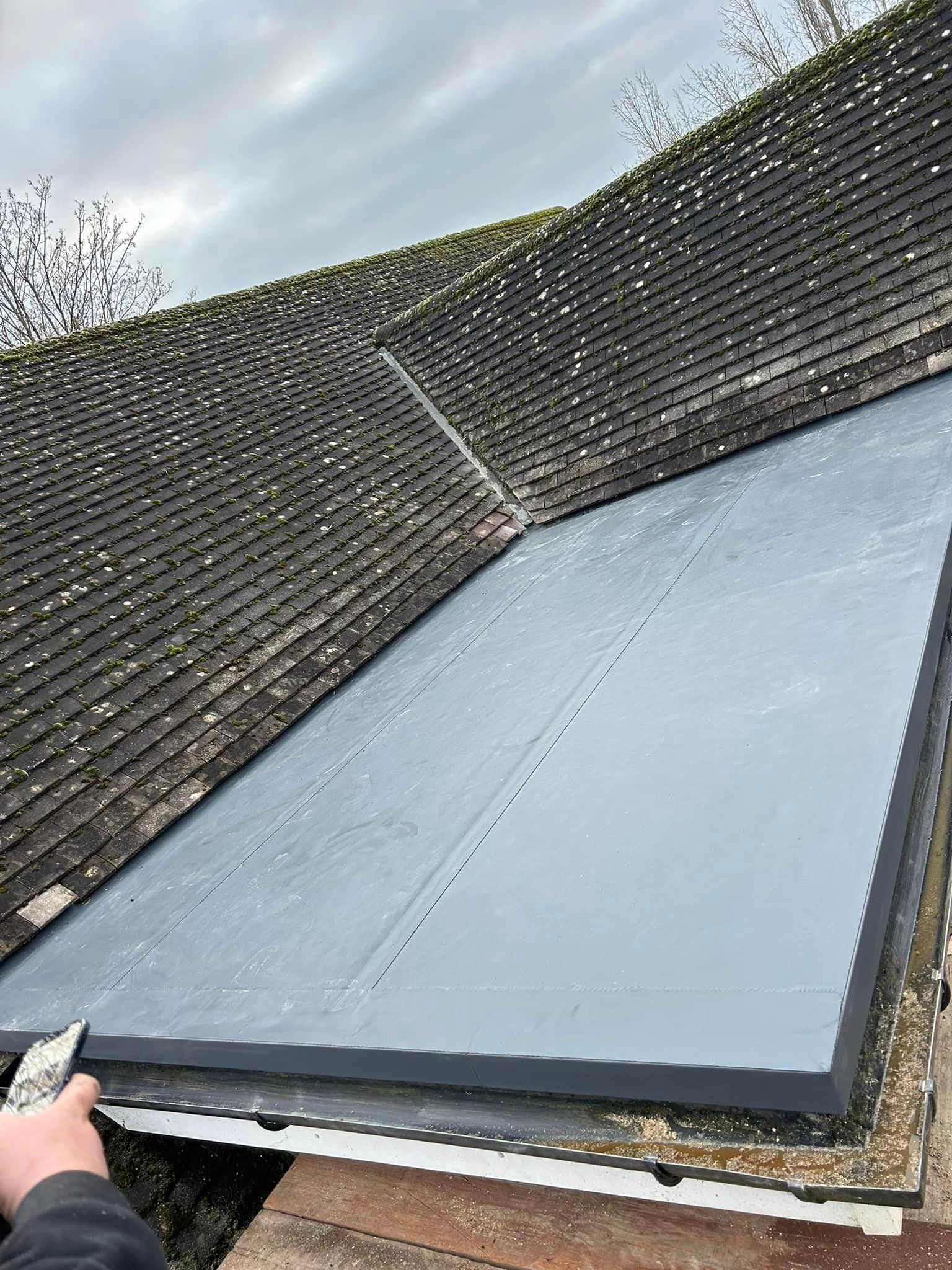A flat modern roof as an extension of a traditional tiled roof on a home